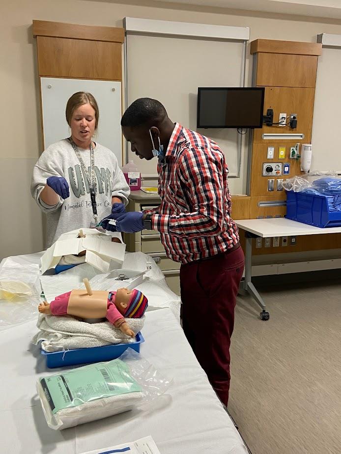 two pediatric residents simulating a medical procedure on a doll